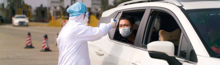 Ein Coronavirus-Kontrollposten in China auf der Autobahn. Die Ärzte kontrollieren die Temperatur eines Fahrgastes.