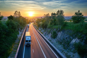 LKW auf einer Straße mit Sonnenuntergang im Hintergrund