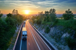 Trucks on a street with sunset in the background