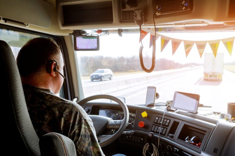 Driver in cabin of big modern truck vehicle on highway