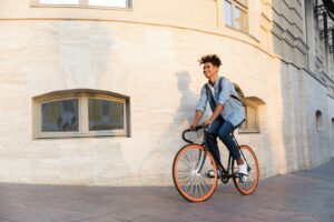 Mann fährt auf Fahrrad um eine Häuserecke