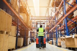 Warehouse clerk with forklift in high-bay warehouse