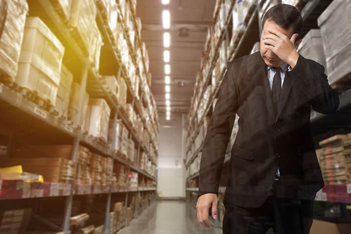 Man in business outfit standing in warehouse looking desperate