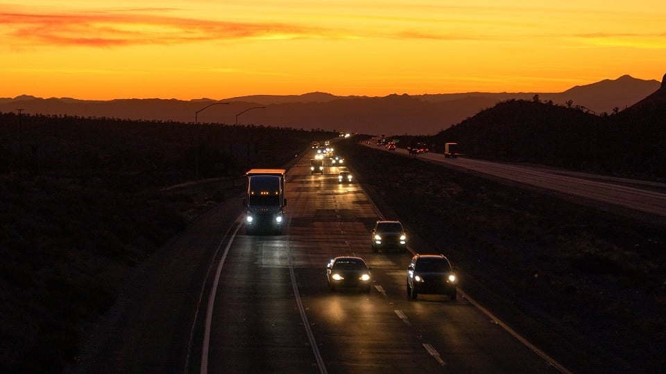 AERIAL: Commuters and trucks drive on the Mojave Freeway at sunset