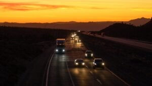 AERIAL: Pendler und LKW fahren auf dem Mojave Freeway bei Sonnenuntergang