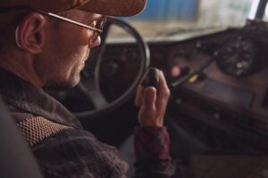 Zwei-Wege-CB-Funk Kommunikation im LKW. LKW-Fahrer in den 40ern im Gespräch mit eingebautem Lkw-Kabinenfunk. Transport und Kommunikation Thema.