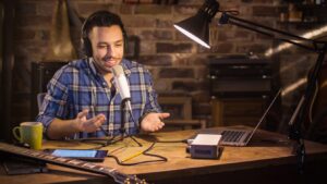 A young man makes a podcast audio recording at home in a garage.