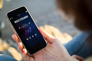 Close-up of a young woman checking her mobile phone to listen to streaming music. All screen graphics are fictional.