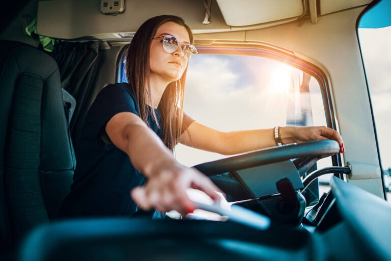 Porträt einer Frau als professioneller LKW-Fahrer, die einen LKW fährt.