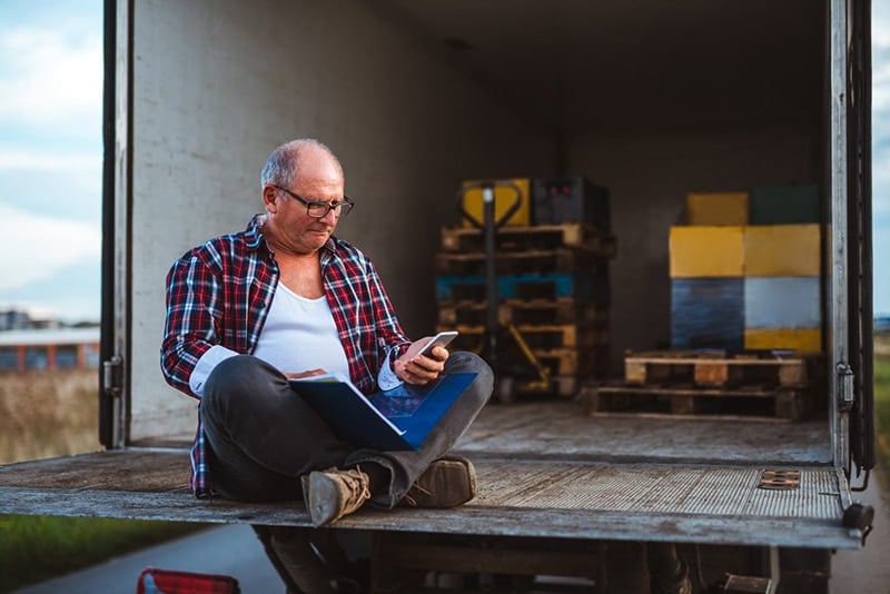 How digital transformation drives sustainability in logistics, Truck driver typing on his cell phone