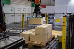 Industrial robot arm loading carton on conveyor in manufacturing production line